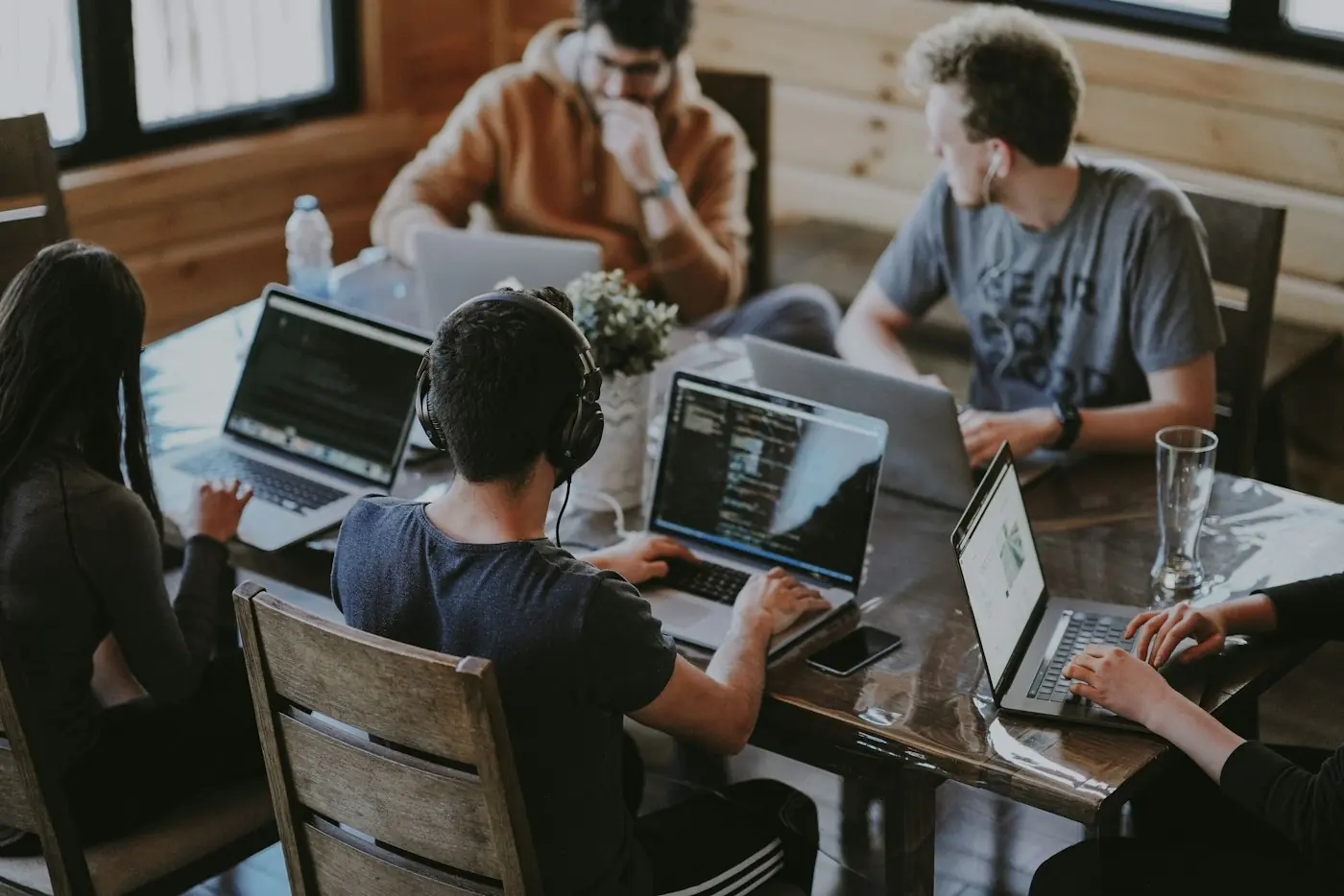Tim sedang bekerja bersama di satu meja dengan laptop