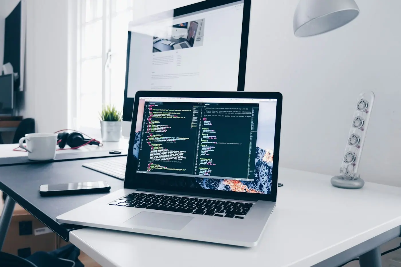 Laptop menampilkan kode website di meja kerja